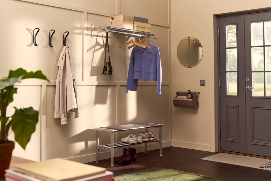 A welcoming and organized hallway with endless hook in forest green, Nostalgi 291 hat rack and Nostalgi bench in chrome and aluminium, Tillbakblick mirror in birch and Ulrika storage in natural wool